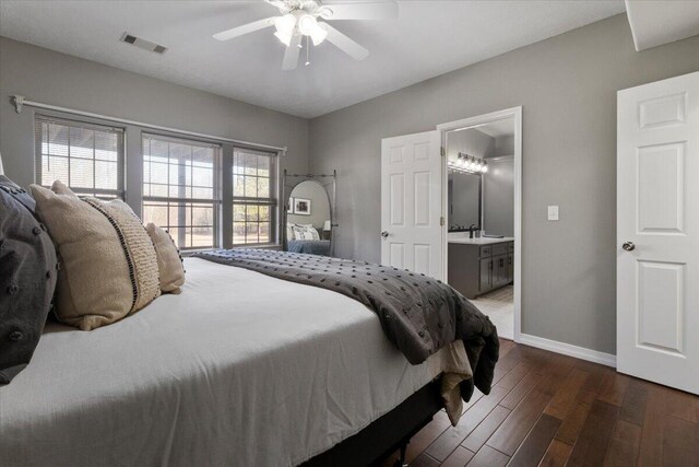 bedroom with a ceiling fan, wood finished floors, visible vents, baseboards, and ensuite bathroom