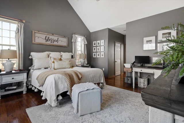 bedroom with high vaulted ceiling and wood finished floors