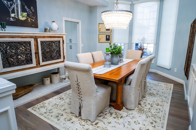 dining room featuring a chandelier, baseboards, and wood finished floors