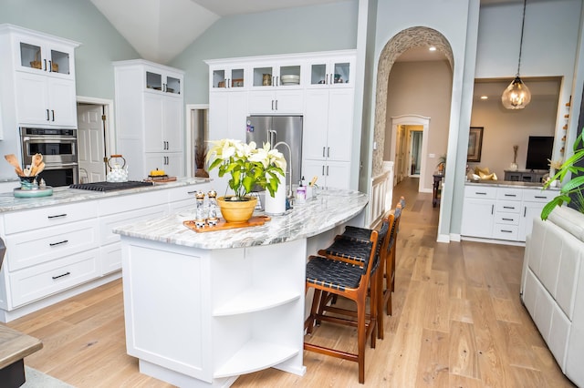 kitchen with light wood-type flooring, stainless steel appliances, arched walkways, and white cabinets