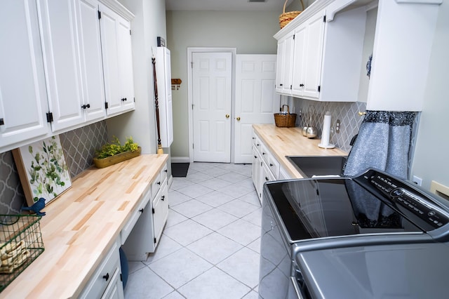 kitchen featuring white cabinetry, light tile patterned floors, decorative backsplash, wooden counters, and stove