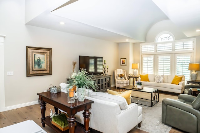 living room featuring vaulted ceiling, recessed lighting, baseboards, and wood finished floors