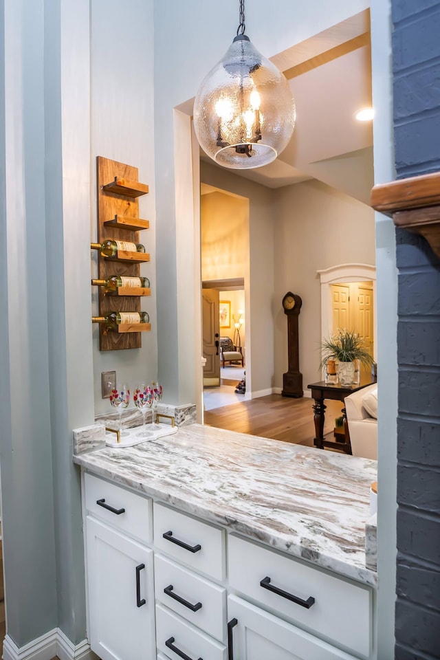 interior space featuring a notable chandelier, white cabinets, light stone counters, and decorative light fixtures