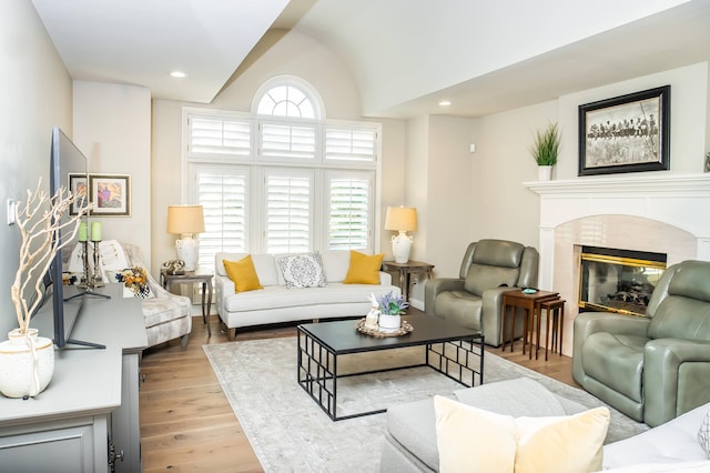 living area with a high end fireplace, vaulted ceiling, recessed lighting, and wood finished floors