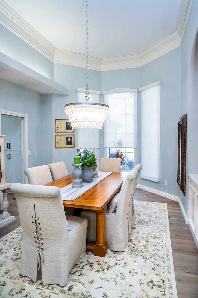 dining room with wood finished floors, baseboards, arched walkways, ornamental molding, and a chandelier