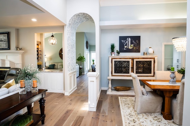 interior space featuring arched walkways, a fireplace, an inviting chandelier, and wood finished floors