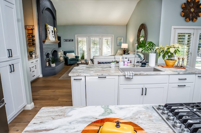 kitchen with stainless steel gas cooktop, open floor plan, wood finished floors, and a sink