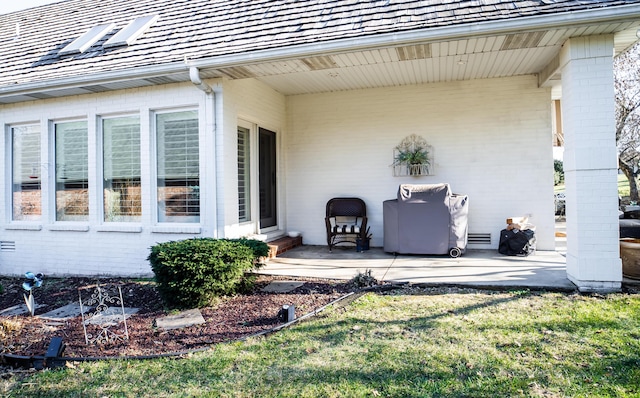 exterior space with brick siding, a lawn, and a patio area