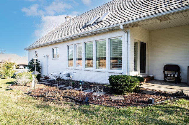 view of side of property featuring entry steps, a lawn, and brick siding