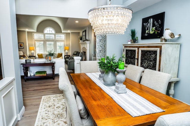 dining space featuring recessed lighting, an inviting chandelier, wood finished floors, and a fireplace