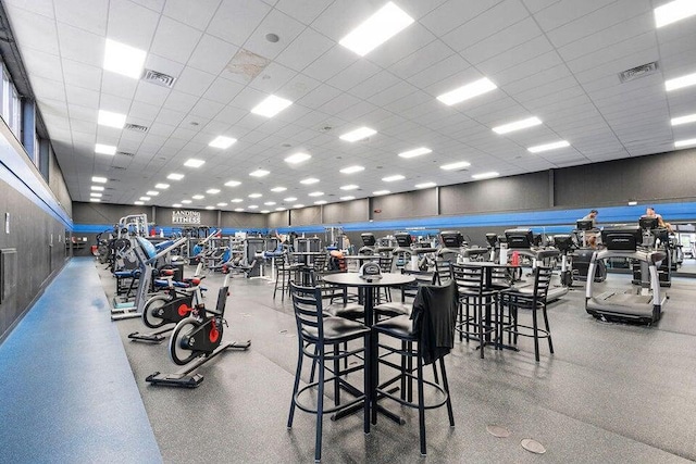 gym with a paneled ceiling and visible vents