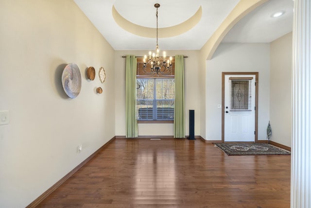 entryway with arched walkways, wood finished floors, baseboards, and a chandelier