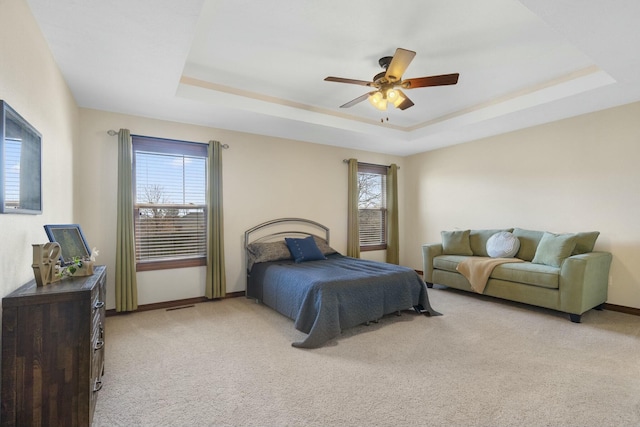 bedroom with light colored carpet, baseboards, and a tray ceiling