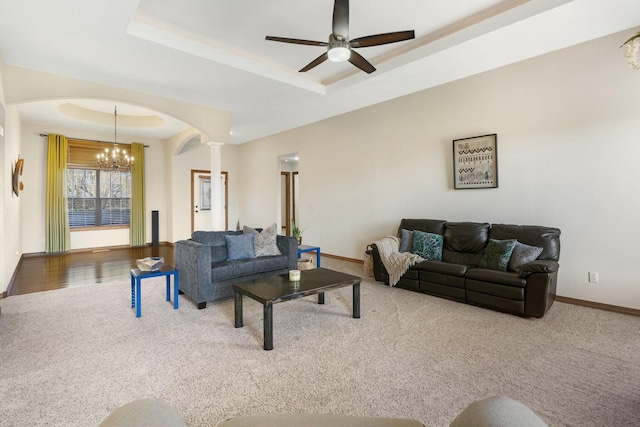 living room with a raised ceiling, arched walkways, and carpet flooring