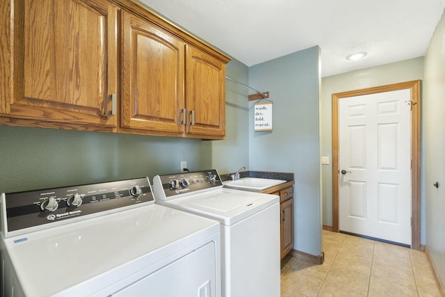 clothes washing area featuring a sink, washer and dryer, cabinet space, light tile patterned floors, and baseboards