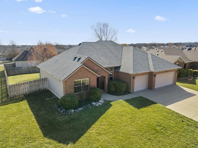 view of front facade featuring a front yard, fence, driveway, an attached garage, and brick siding