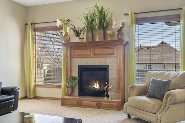 carpeted living room featuring visible vents, baseboards, and a tiled fireplace