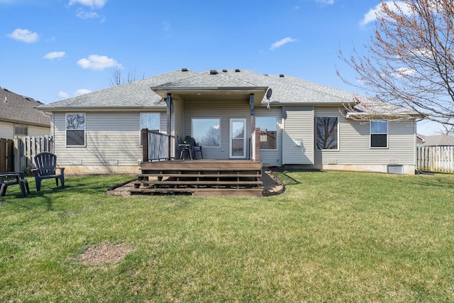 rear view of house featuring a shingled roof, a wooden deck, a yard, and fence