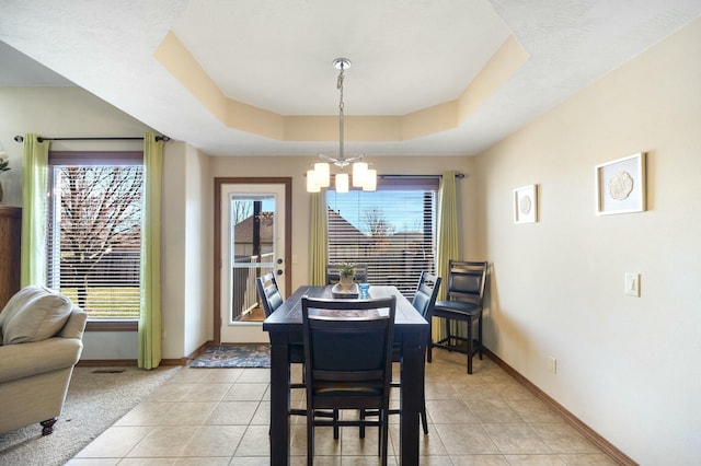 dining space featuring light tile patterned floors, a tray ceiling, baseboards, and an inviting chandelier