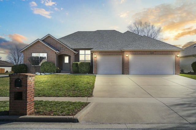 view of front facade with an attached garage, a lawn, driveway, and roof with shingles