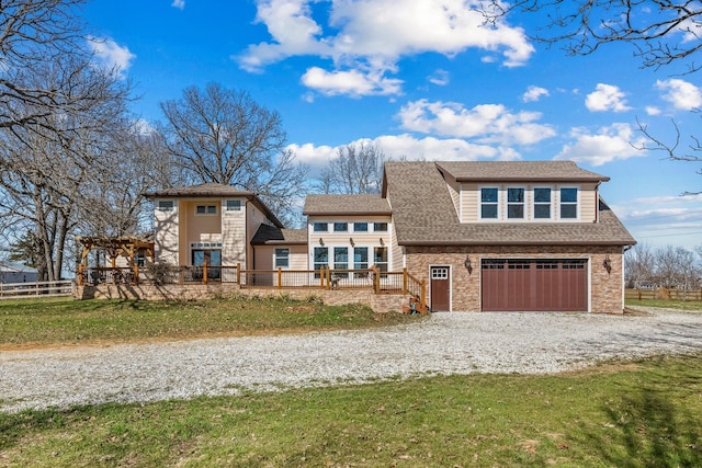 view of front of property with an attached garage, gravel driveway, a front lawn, and fence