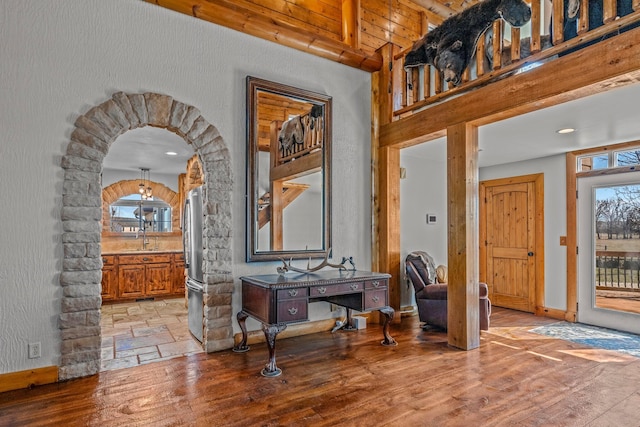 foyer with light wood-style floors, arched walkways, and baseboards