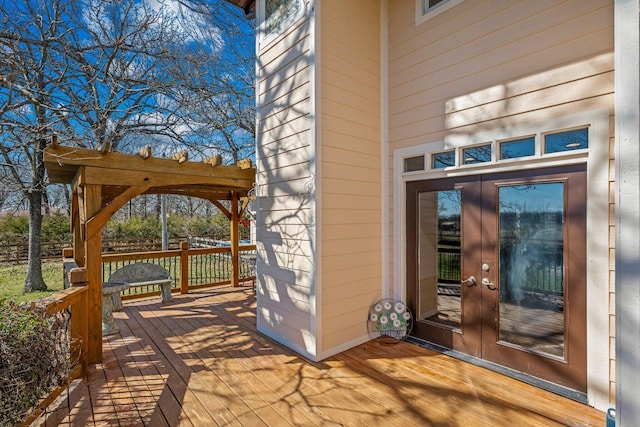 view of exterior entry featuring french doors, a pergola, and a wooden deck