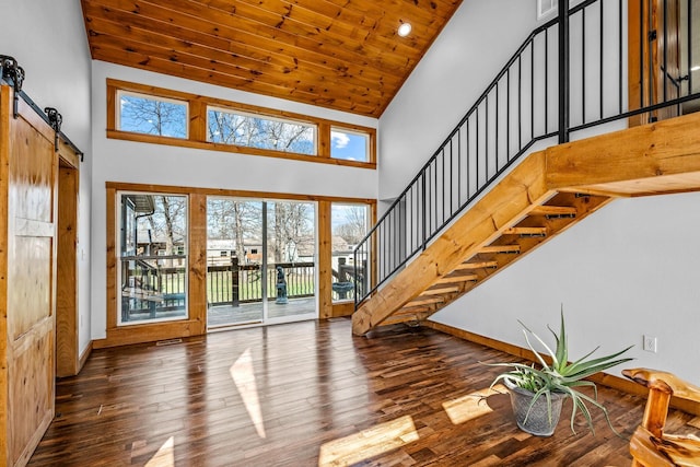 foyer with wood ceiling, stairs, a barn door, hardwood / wood-style floors, and a high ceiling