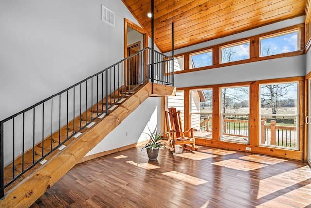 stairway with wooden ceiling, wood finished floors, visible vents, and high vaulted ceiling