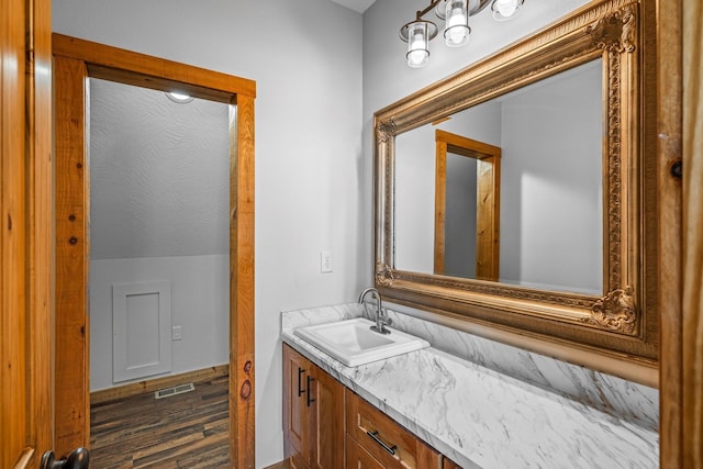 bathroom with visible vents, wood finished floors, vanity, and vaulted ceiling