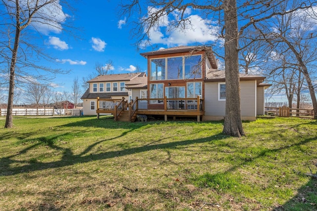 back of property featuring a lawn, a deck, and fence