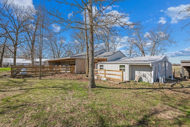 back of property featuring ac unit, a yard, metal roof, and fence