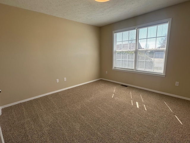 carpeted empty room featuring visible vents, a textured ceiling, and baseboards