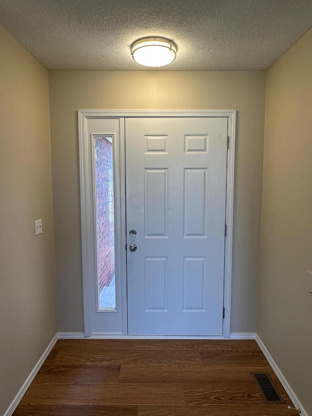 foyer featuring dark wood-type flooring, baseboards, and visible vents