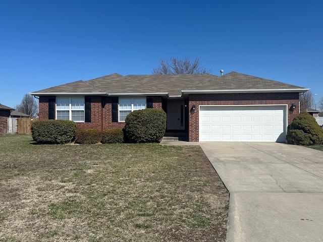 ranch-style home with a front lawn, roof with shingles, concrete driveway, a garage, and brick siding