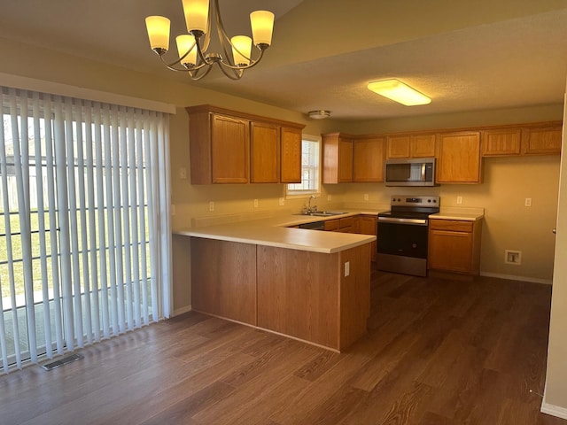 kitchen featuring visible vents, a peninsula, a sink, dark wood-type flooring, and appliances with stainless steel finishes