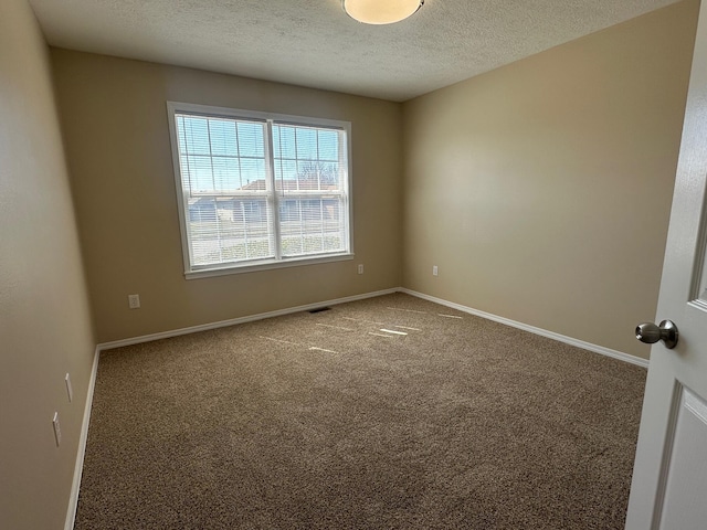 carpeted empty room featuring visible vents, a textured ceiling, and baseboards