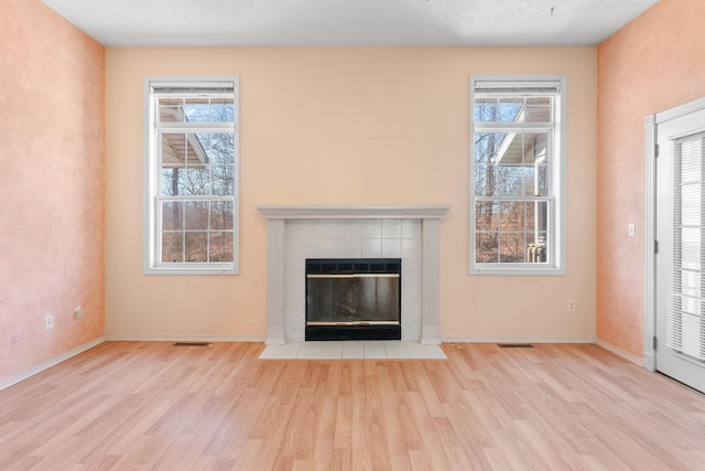 unfurnished living room featuring visible vents, a fireplace, baseboards, and wood finished floors