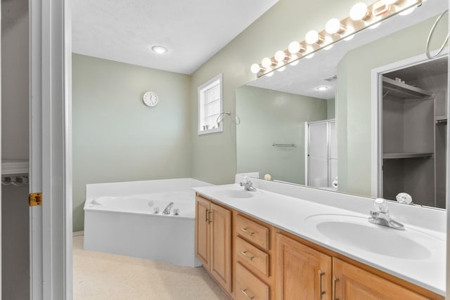 full bathroom with double vanity, a sink, a shower stall, a textured ceiling, and a garden tub