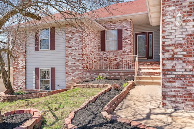 exterior space featuring entry steps, brick siding, and roof with shingles