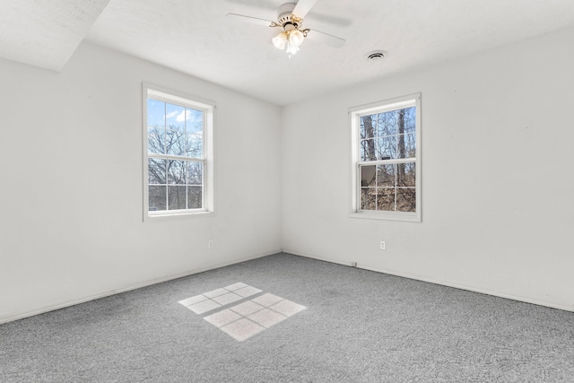 carpeted empty room featuring visible vents and ceiling fan