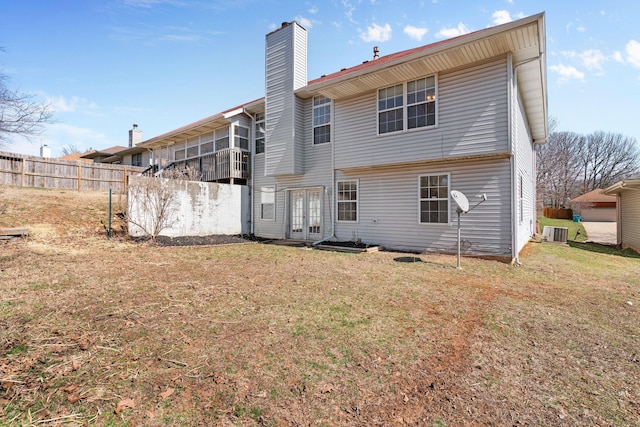 back of house with cooling unit, fence, a yard, a chimney, and french doors