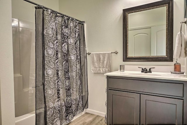 full bath with baseboards, wood finished floors, vanity, and shower / bath combination with curtain