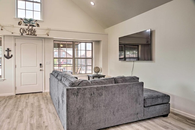 living room with baseboards, high vaulted ceiling, a healthy amount of sunlight, and light wood-style flooring