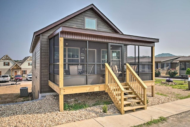 view of front of house featuring a residential view, central AC, and a sunroom