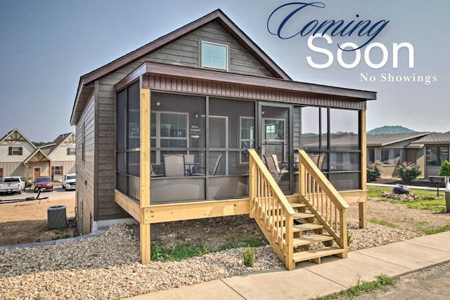 view of front of home with central air condition unit, a residential view, and a sunroom