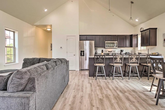 living room featuring recessed lighting, high vaulted ceiling, and light wood-style flooring