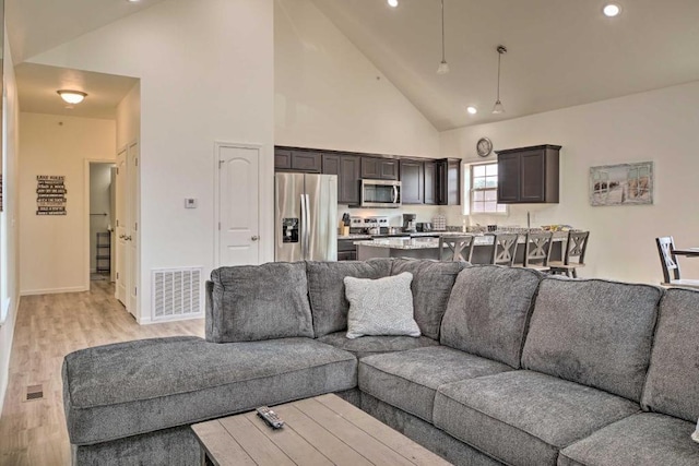 living room featuring visible vents, recessed lighting, high vaulted ceiling, and light wood-type flooring