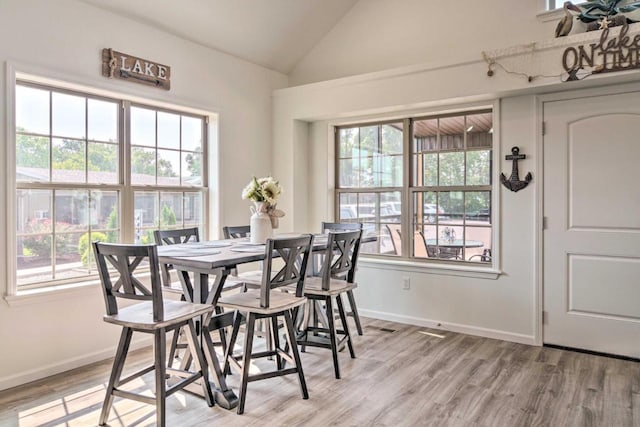 dining room featuring lofted ceiling, baseboards, and light wood-type flooring