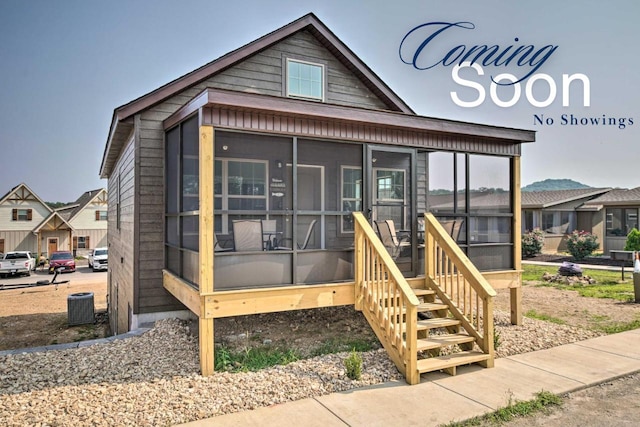 view of front facade with cooling unit, a residential view, and a sunroom